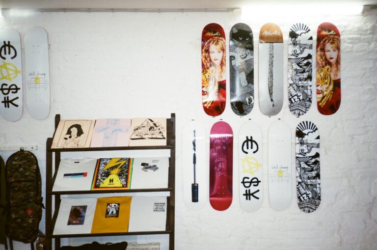 A collection of artistic skateboards and prints displayed on a white brick wall, showcasing modern art and design.