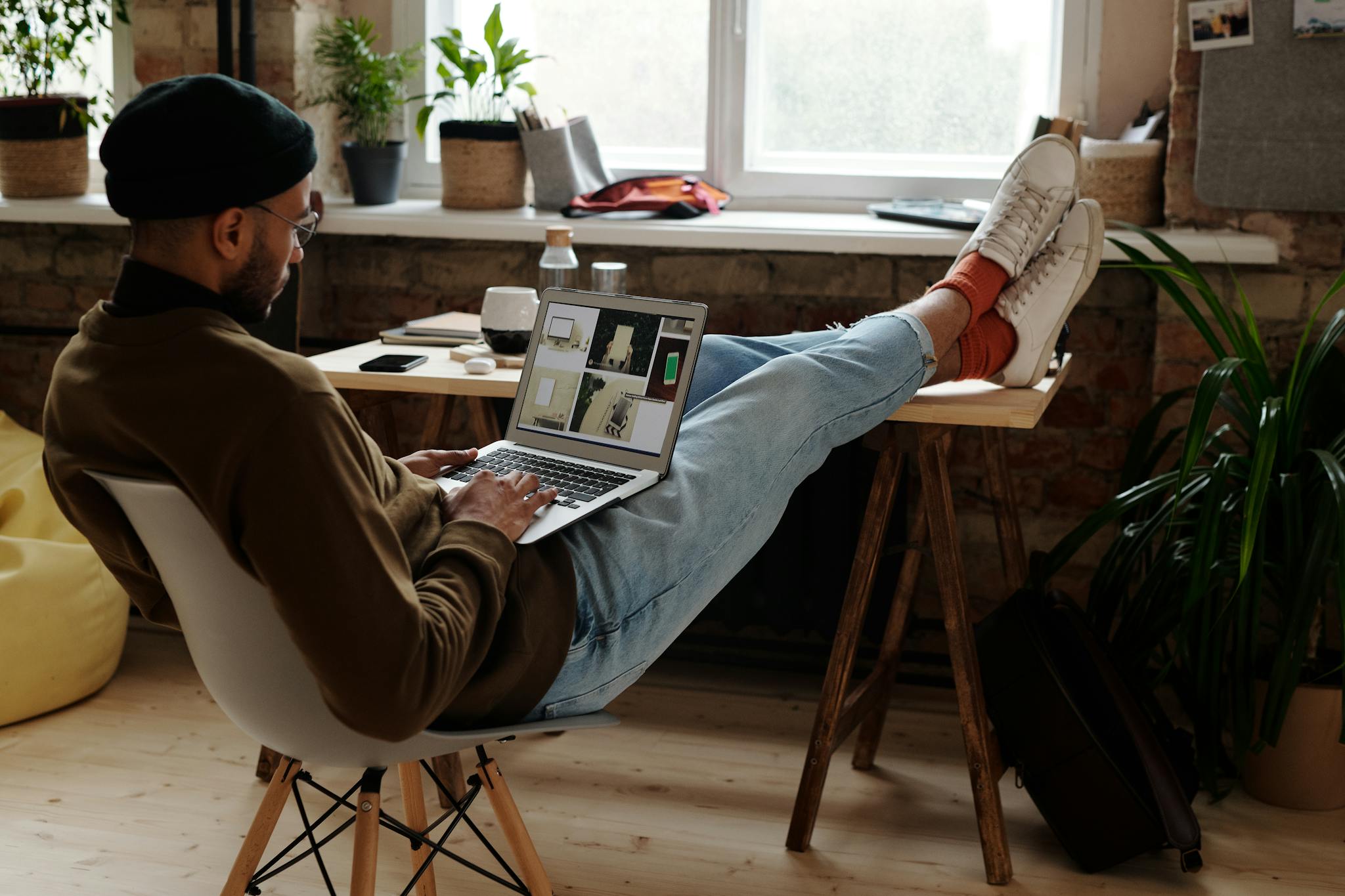 Man working remotely from home in a modern setup with laptop and gadgets.